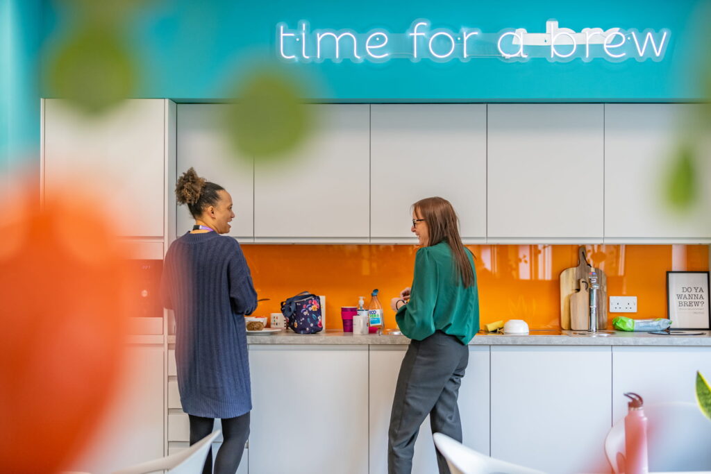 Staff laugh over a coffee in a bright and welcoming office kitchen